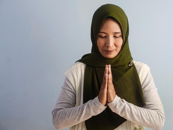 A portrait of Asian woman posing for thank you body language by putting her both hand together in the front. Copy space, empty space.