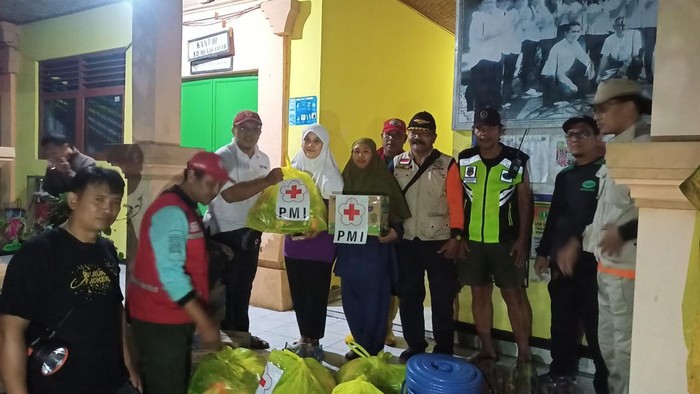 Petugas PMI Tabanan menyerahkan bantuan alas tempat tidur dan peralatan kebersihan bagi pengungsi di SDN 6 Sanggulan, Jumat (7/7/2023) malam. (chairul amri simabur/detikBali)