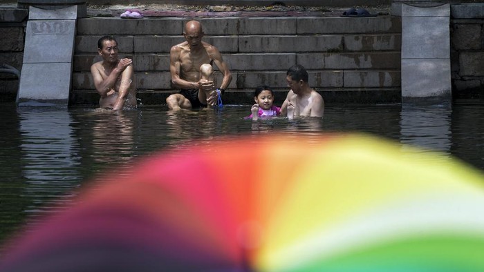 Cara Warga Beijing Hadapi Cuaca Panas Menyengat Residents cool off from a sweltering day at an urban waterway in Beijing, Thursday, July 6, 2023. Employers in Beijing were ordered Thursday by the government to stop outdoor work after scorching summer heat in the Chinese capital was forecast to reach 40 degrees centigrade (104 Fahrenheit). (AP Photo/Andy Wong)