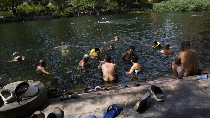 Cara Warga Beijing Hadapi Cuaca Panas Menyengat Residents cool off from a sweltering day at an urban waterway in Beijing, Thursday, July 6, 2023. Employers in Beijing were ordered Thursday by the government to stop outdoor work after scorching summer heat in the Chinese capital was forecast to reach 40 degrees centigrade (104 Fahrenheit). (AP Photo/Andy Wong)