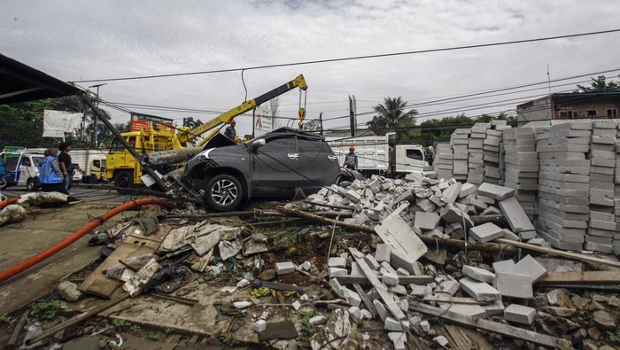 Pekerja PLN melakukan evakuasi tiang listrik yang menimpa mobil saat terjadi kecelakaan di Jalan Raya Parung, Kemang, Kabupaten Bogor, Jawa Barat, Jumat (7/7/2023). Kecelakaan yang melibatkan mobil dan truk yang menghantam tiang listrik  itu tidak menimbulkan korban jiwa namun menyebabkan kemacetan lalu lintas di kawasan tersebut. ANTARA FOTO/Yulius Satria Wijaya/foc.