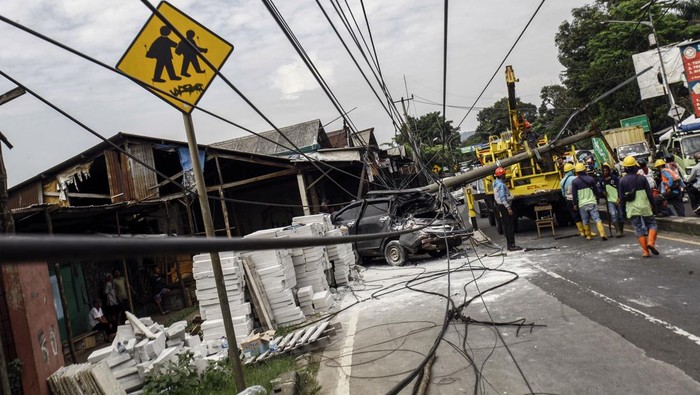 Pekerja PLN melakukan evakuasi tiang listrik yang menimpa mobil saat terjadi kecelakaan di Jalan Raya Parung, Kemang, Kabupaten Bogor, Jawa Barat, Jumat (7/7/2023). Kecelakaan yang melibatkan mobil dan truk yang menghantam tiang listrik  itu tidak menimbulkan korban jiwa namun menyebabkan kemacetan lalu lintas di kawasan tersebut. ANTARA FOTO/Yulius Satria Wijaya/foc.