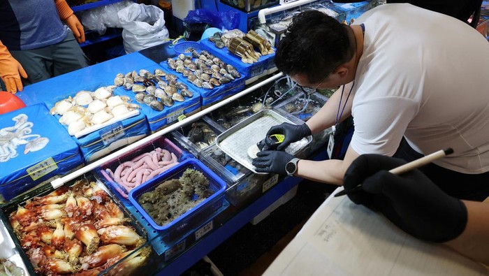 Makanan Laut di Pasar Ikan Korsel Dicek, Waspada Radiasi An official measures radiation levels of scallops imported from Japan as they conduct a radioactivity check, which have been conducted regularly since the 2011 Fukushima disaster, at Noryangjin fisheries wholesale market in Seoul, South Korea, July 6, 2023. REUTERS/Kim Hong-Ji
