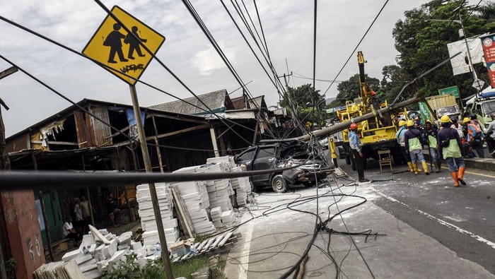 Pekerja PLN melakukan evakuasi tiang listrik yang menimpa mobil  saat terjadi kecelakaan di Jalan Raya Parung, Kemang, Kabupaten Bogor, Jawa Barat, Jumat (7/7/2023). Kecelakaan yang melibatkan mobil dan truk yang menghantam tiang listrik  itu tidak menimbulkan korban jiwa namun menyebabkan kemacetan lalu lintas di kawasan tersebut. ANTARA FOTO/Yulius Satria Wijaya/foc.