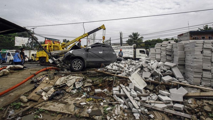 Pekerja PLN melakukan evakuasi tiang listrik yang menimpa mobil saat terjadi kecelakaan di Jalan Raya Parung, Kemang, Kabupaten Bogor, Jawa Barat, Jumat (7/7/2023). Kecelakaan yang melibatkan mobil dan truk yang menghantam tiang listrik itu tidak menimbulkan korban jiwa namun menyebabkan kemacetan lalu lintas di kawasan tersebut. ANTARA FOTO/Yulius Satria Wijaya/foc.