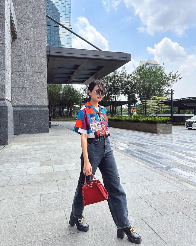 Maudy Ayunda tampil casual namun tetap menonjolkan statement gaya dengan kemeja berwarna cerah, boyfriend jeans dan platform shoes. Foto: Instagram/@maudyayunda