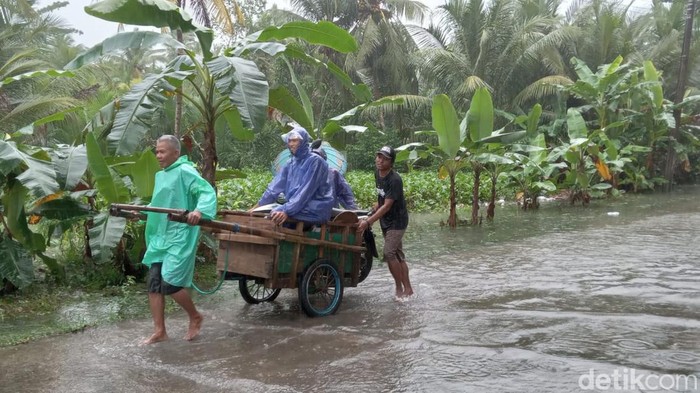 Warga manfaatkan jasa ojek gerobak untuk lewati banjir.