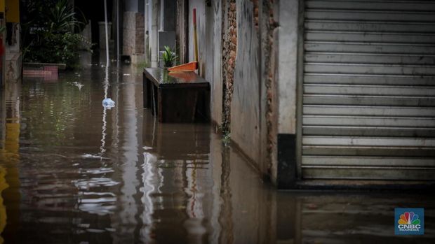 Warga melintas saat terjadi banjir pada pemukiman warga di kawasan Petogogan, Jakarta Selatan, Jumat (7/7/2023). (CNBC Indonesia/Faisal Rahman)