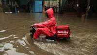 Seorang pengantar makanan mengarungi jalan yang banjir setelah hujan lebat di New Delhi, India, 8 Juli 2023. 