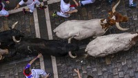 Para peserta berlari di depan banteng selama acara encierro (lari banteng) saat festival San Fermin di Pamplona, Spanyol, Minggu (9/7). 