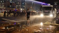Polisi berusaha memmubarkan pendemo dengan water cannon. 