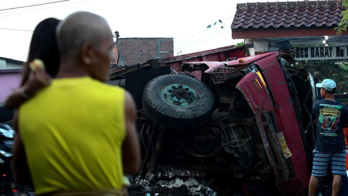 Kecelakaan truk muatan pupuk timpa rumah Warga menyaksikan truk terguling yang menimpa rumah di Greges Barat, Surabaya, Jawa Timur, Minggu (9/7/2023). Truk bernomor polisi L 9476 OA dengan muatan pupuk curah itu terguling dan menimpa rumah setelah menghindari kendaraan dari arah berlawanan yang mengakibatkan seorang penghuni rumah meninggal. ANTARA FOTO/Didik Suhartono/tom.