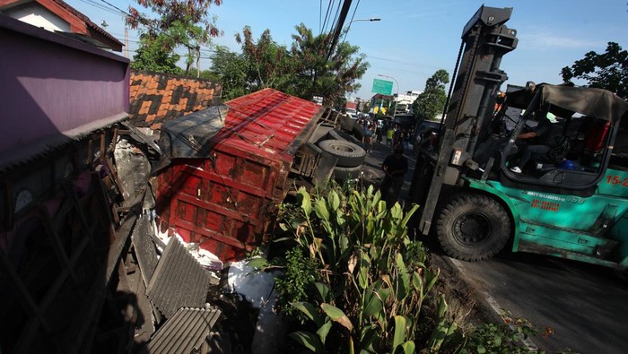 Kecelakaan truk muatan pupuk timpa rumah Warga menyaksikan truk terguling yang menimpa rumah di Greges Barat, Surabaya, Jawa Timur, Minggu (9/7/2023). Truk bernomor polisi L 9476 OA dengan muatan pupuk curah itu terguling dan menimpa rumah setelah menghindari kendaraan dari arah berlawanan yang mengakibatkan seorang penghuni rumah meninggal. ANTARA FOTO/Didik Suhartono/tom.