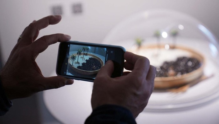 A person takes a picture of a piece or art of 'Japan in Miniatures' exhibition, by Japanese photographer Tatsuya Tanaka, that shows scenes of Japanese daily life portrayed in miniatures, at Japan House in Sao Paulo, Brazil July 7, 2023. REUTERS/Leonardo Benassatto  NO RESALES. NO ARCHIVES