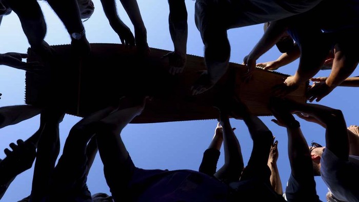 Muslim men carry coffins with remains of the victims of the 1995 Srebrenica genocide, in Potocari, Bosnia, Sunday, July 9, 2023. The remains of the 30 recently identified victims of Srebrenica massacre, Europe's only acknowledged genocide since World War II, arrived at the Memorial centre in Potocari where they will be buried on July 11. (AP Photo/Armin Durgut)