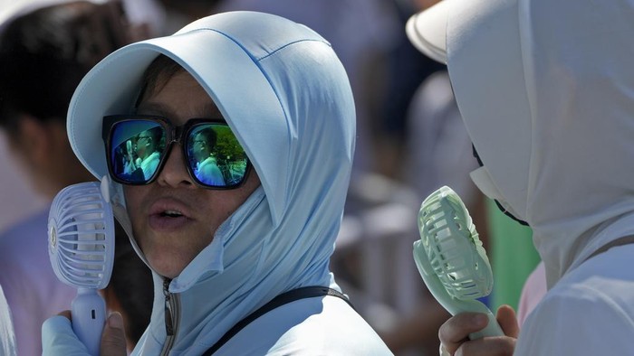 Beragam Aksi Warga di Berbagai Negara Hadapi Panas Ekstrem Women wearing sun protection clothing cool themselves with electric fans as visitors line up to visit the Panda enclosure on a sweltering day at a zoo in Beijing, Sunday, July 9, 2023. Earlier this week, Beijing reported more than nine straight days with temperatures above 35 degrees Celsius (95 degrees Fahrenheit), a streak unseen since 1961. (AP Photo/Andy Wong)