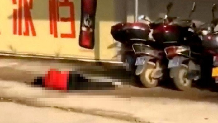SENSITIVE MATERIAL. THIS IMAGE MAY OFFEND OR DISTURB A body lies on the ground near people riding a scooter in the aftermath of a stabbing attack at a kindergarten in Lianjiang county, Guangdong province, China in this still image obtained from social media video released July 10, 2023. Video obtained by Reuters/via REUTERS THIS IMAGE HAS BEEN SUPPLIED BY A THIRD PARTY. MANDATORY CREDIT. NO RESALES. NO ARCHIVES.