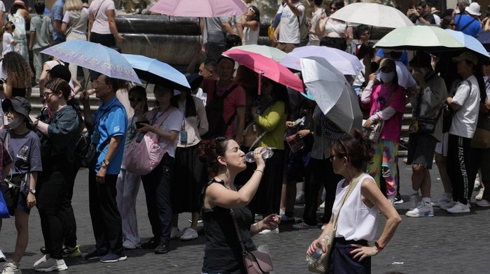Tourists use umbrellas to shelter from the sun as they queue to enter the Pantheon in Rome, Saturday, July 8, 2023. An intense heat wave has reached Italy, bringing temperatures close to 40 degrees Celsius in many cities across the country. (AP Photo/Gregorio Borgia)