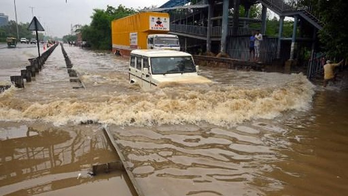 A commuter drives his car along a flooded highway after heavy monsoon rains in Gurgaon on the outskirts of New Delhi on July 9, 2023. (Photo by AFP)