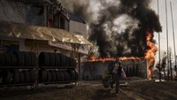 Seorang pria berlari sambil mengambil barang-barang dari toko yang terbakar setelah serangan Rusia di Kharkiv, Ukraina, Jumat, 25 Maret 2022. Sementara pertempuran sebagian besar menemui jalan buntu, pemerintah Ukraina dan pendukung Baratnya berharap serangan balasan luas yang diluncurkan bulan lalu akan mengubah garis pertempuran dan mengembalikan wilayah yang diduduki Rusia ke kendali Ukraina. AP/Felipe Dana