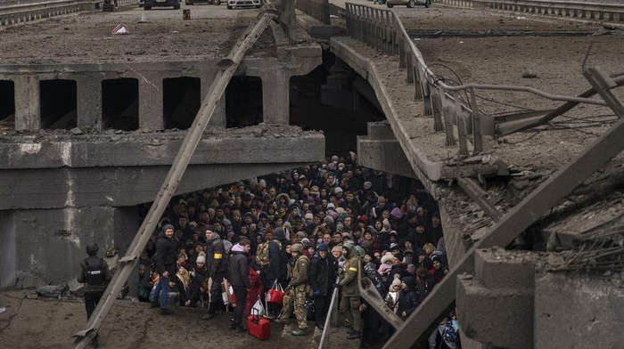 Ukrainians crowd under a destroyed bridge as they try to flee by crossing the Irpin River on the outskirts of Kyiv, Ukraine, Saturday, March 5, 2022. (AP Photo/ Emilio Morenatti)