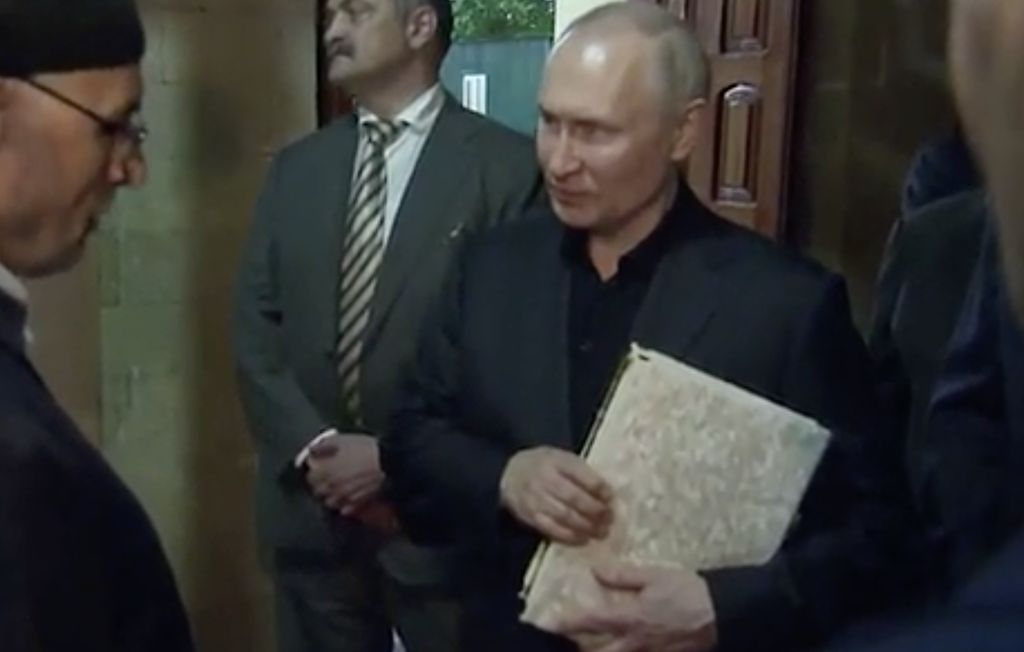 Presiden Rusia, Vladimir Putin pegang Al Qur'an. (Tangakapan Layar/REUTERS)