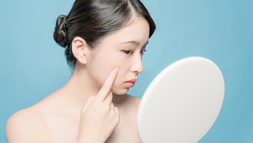 Asian girl checking her skin.