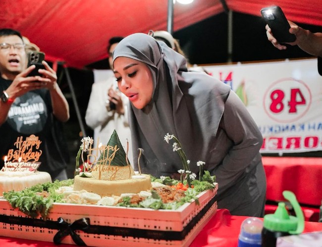 Ada pula momen tiup lilin di warung tenda menggunakan nasi kuning. Aurel tampil sederhana mengenakan hijab instan dan piyama warna abu. Foto: Instagram @attahalilintar