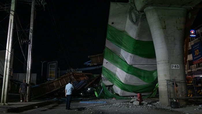 People look on after a construction girder on an elevated tollway collapsed, killing at least one person, in Lat Krabang district in Bangkok on July 10, 2023. (Photo by Tananchai KEAWSOWATTANA / THAI NEWS PIX / AFP)