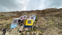 Orang-orang duduk di luar kabin lereng bukit di Kota Sanaa, Yaman, Kamis (6/7/2023).  
