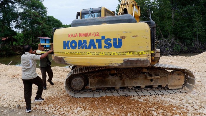 Petugas memasang garis polisi pada alat berat di area hutan mangrove yang telah ditimbun di Kawasan konservasi Taman Wisata Alam (TWA) Teluk Youtefa, Kota Jayapura, Papua, Selasa (11/7/2023). Penimbunan dan pembabatan hutan mangrove untuk keperluan pembangunan tersebut dihentikan oleh Dinas Kehutanan Provinsi Papua, BBKSDA Papua, Gakkum, masyarakat adat dan kepolisian karena merupakan kawasan konservasi yang harus dilindungi dan dinilai merusak lingkungan. ANTARA FOTO/Sakti Karuru/foc.