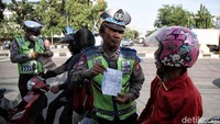 Polisi memberikan surat tilang kepada pengendara yang melanggar.  