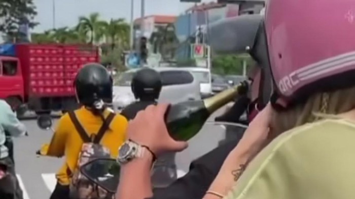 Tangkapan layar video pasangan WNA yang diduga menenggak minuman keras (miras) sembari mengendarai sepeda motor viral di media sosial.