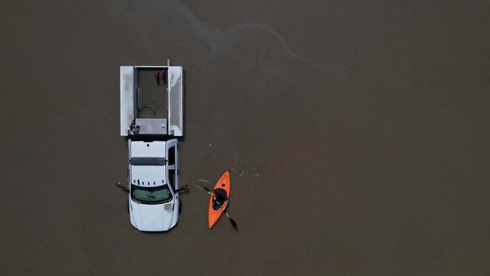 Banjir Bikin Montpelier Seperti Danau, Mobil-mobil Ini Jadi Korban A person in a canoe passes cars partially submerged by flood waters from recent rain storms in Montpelier, Vermont, U.S., July 11, 2023. REUTERS/Brian Snyder