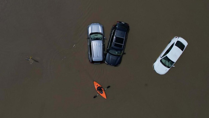 Banjir Bikin Montpelier Seperti Danau, Mobil-mobil Ini Jadi Korban A person in a canoe passes cars partially submerged by flood waters from recent rain storms in Montpelier, Vermont, U.S., July 11, 2023. REUTERS/Brian Snyder