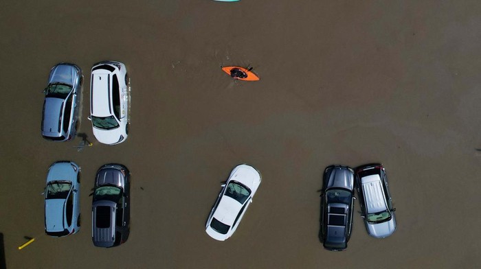 Banjir Bikin Montpelier Seperti Danau, Mobil-mobil Ini Jadi Korban A person in a canoe passes cars partially submerged by flood waters from recent rain storms in Montpelier, Vermont, U.S., July 11, 2023. REUTERS/Brian Snyder