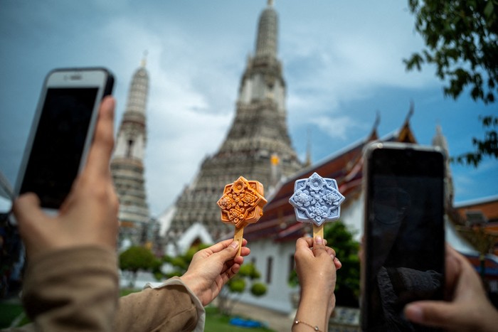 People take pictures of ice cream shaped like tiles of the famous Wat Arun temple, or Temple of Dawn, in Bangkok, Thailand July 8, 2023. REUTERS/Athit Perawongmetha