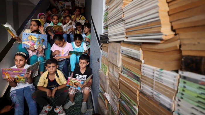 Pria di Mesir Ubah Rumahnya Jadi Perpustakaan Terbuka Mohamed Abdel Aziz, 34, interacts with children in a field, in front of his house which has been turned into a free learning centre for village students who lack access to cultural services and activities, at Bishet Amer village in the Sharqia Governorate, north of Cairo, Egypt, July 10, 2023. REUTERS/Mohamed Abd El Ghany