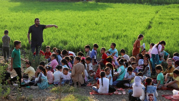 Pria di Mesir Ubah Rumahnya Jadi Perpustakaan Terbuka Mohamed Abdel Aziz, 34, interacts with children in a field, in front of his house which has been turned into a free learning centre for village students who lack access to cultural services and activities, at Bishet Amer village in the Sharqia Governorate, north of Cairo, Egypt, July 10, 2023. REUTERS/Mohamed Abd El Ghany