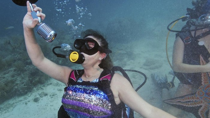 'Putri Duyung' Gelar Konser Musik Untuk Pelestarian Terumbu Karang In this photo provided by the Florida Keys News Bureau, Tamara Bredova, left, costumed as a mermaid, pretends to play a ukulele underwater, Saturday, July 8, 2023, while Kelly Angel, right, strokes a faux guitar at the Lower Keys Underwater Music Festival in the Florida Keys National Marine Sanctuary near Big Pine Key, Fla. Several hundred divers and snorkelers submerged along a portion of the continental United States' only living coral barrier reef to listen to a local radio station's four-hour broadcast, piped beneath the sea to promote coral reef preservation. Kelly Angel is at right. (Frazier Nivens/Florida Keys News Bureau via AP)