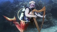 Ratusan penyelam di Florida menggelar acara semacam festival musik di dalam air. Mereka tampil bak putri duyung dan memainkan alat musik, seperti harpa, dalam acara Festival Musik Bawah Air Lower Keys.  