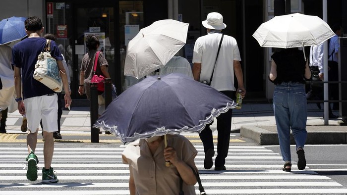 People walk under bright sunlight Wednesday, July 12, 2023, in Tokyo. Hot weather on Wednesday has set with temperatures rising over 36 degrees Celsius (97 degrees Fahrenheit) in Tokyo, according to the Japan Meteorological Agency. (AP Photo/Eugene Hoshiko)
