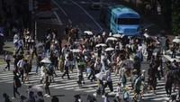 Orang-orang membawa payung untuk melindungi diri dari panas terik matahari saat mereka berjalan melintasi persimpangan di Tokyo, Rabu (12/7/2023). AP/Kiichiro Sato
