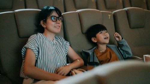 The Asian family is happy as they bring their son to watch their favorite movie, and the boy is very happy.