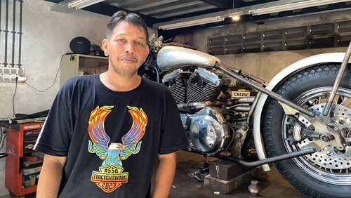 Komang Gede Sentana Putra alias Kedux bersama dengan motor custom buatannya di Kedux Garage, Denpasar, Rabu, (10/05/2023).