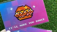 Saat mendapat K-Meals ini, detikfood juga menerima merchandise eksklusif berupa post card. Desainnya berupa pixel art bentuk burger dengan tulisan Ill Make You Dance.