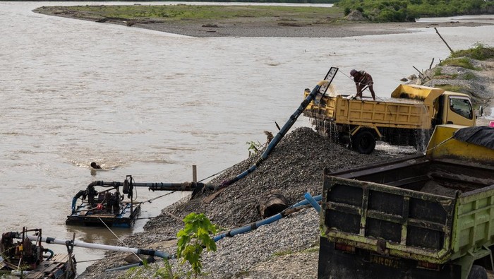 Pekerja meratakan pasir yang disedot dari sungai ke atas truk di kasawan pertambangan  rakyat galian C di Desa Sunju, Sigi, Sualwesi Tengah, Rabu (12/7/2023). Untuk mengatasi pendangkalan sungai yang terus terjadi di wilayah itu dan menekan beban biaya pengerukan, Pemerintah setempat membuka kawasan itu sebagai wilayah pertambangan rakyat galian C berupa pasir dan kerikil sekaligus untuk menambah sumber pendapatan daerah melalui retribusi. ANTARA FOTO/Basri Marzuki/foc.