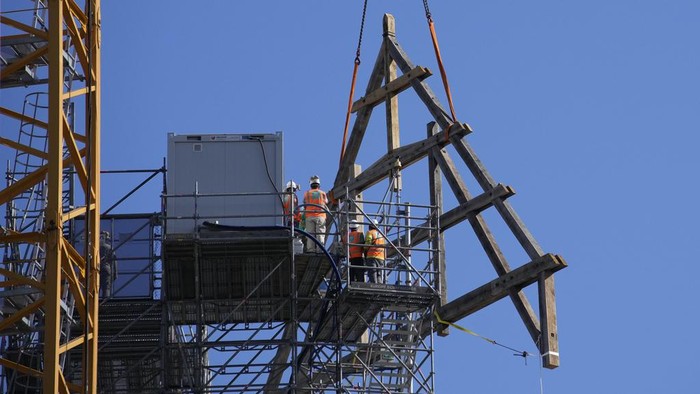 Progres Renovasi Katedral Notre Dame Usai Kebakaran Hebat Workers stand by a huge oak frame at Notre Dame de Paris cathedral, Tuesday, July 11, 2023 in Paris. The panels are due to be reassembled on the top of Notre Dame to replace the roof that flames turned into ashes in 2019. (AP Photo/Christophe Ena)