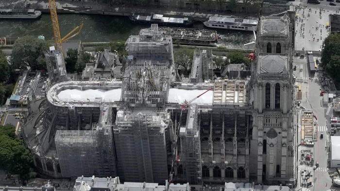 Progres Renovasi Katedral Notre Dame Usai Kebakaran Hebat Workers stand by a huge oak frame at Notre Dame de Paris cathedral, Tuesday, July 11, 2023 in Paris. The panels are due to be reassembled on the top of Notre Dame to replace the roof that flames turned into ashes in 2019. (AP Photo/Christophe Ena)