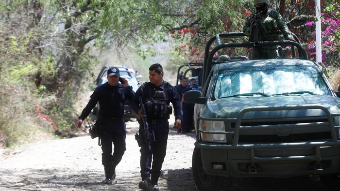 Serangan Bom Tewaskan 6 Orang di Meksiko, TKP Dijaga Ketat Police officers walk by a soldier as they secure a scene where suspected gang members killed police officers and members of the Jalisco state attorney general's office during an attack with explosives on Tuesday night, in Tlajomulco de Zuniga, Mexico July 12, 2023. REUTERS/Fernando Carranza